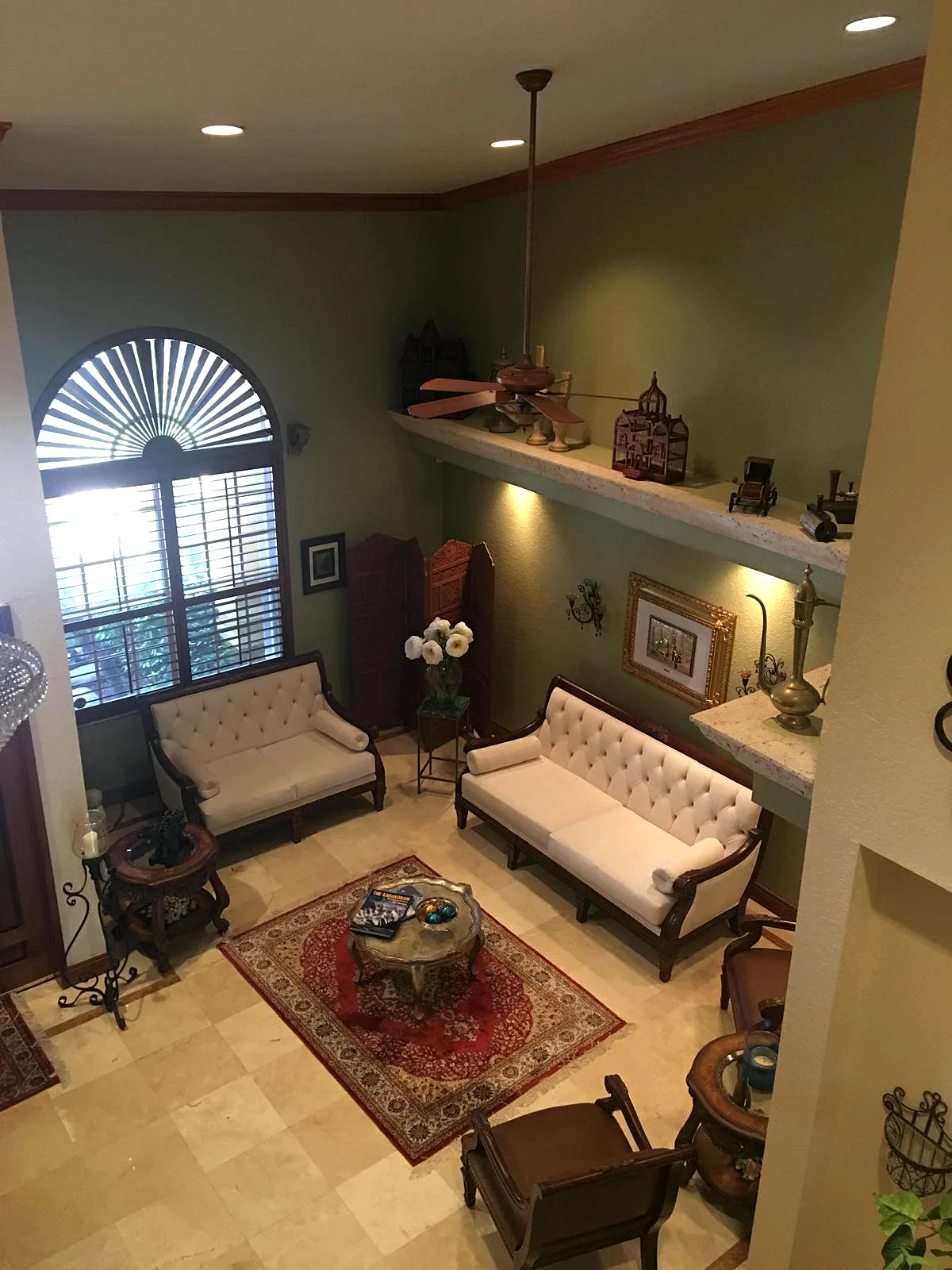 A two-story living room with sage green walls and clean lines at the crown molding