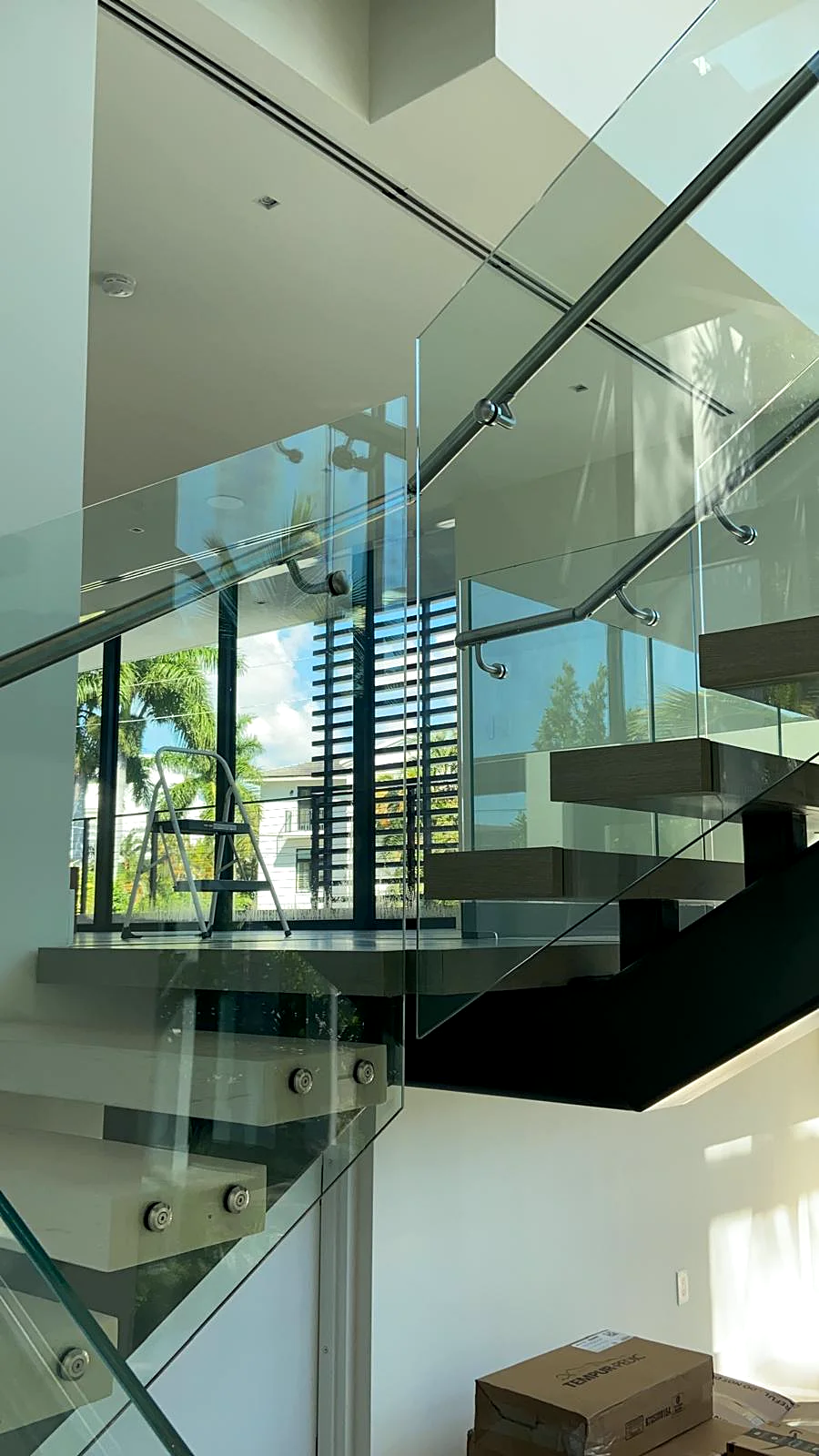 Bright white interior walls around a glass and steel staircase